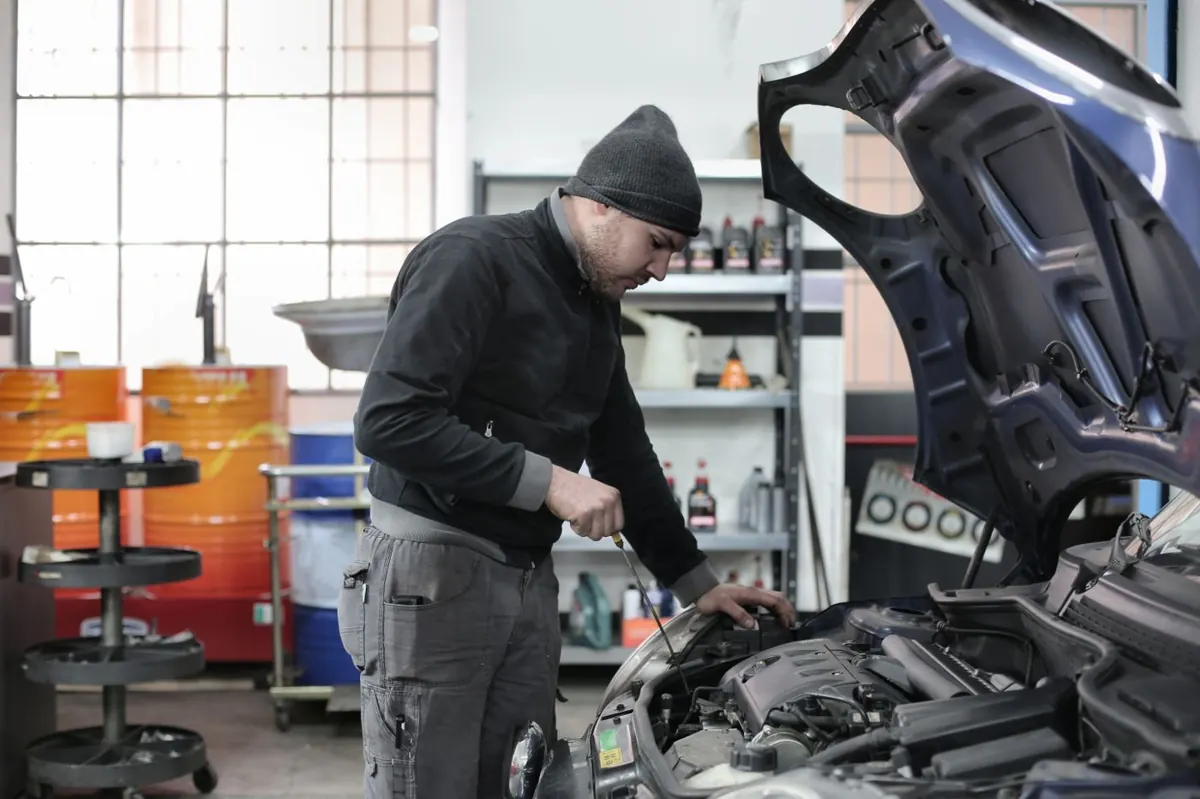 Mécanicien au-dessus d’un moteur, garage, outils autour.